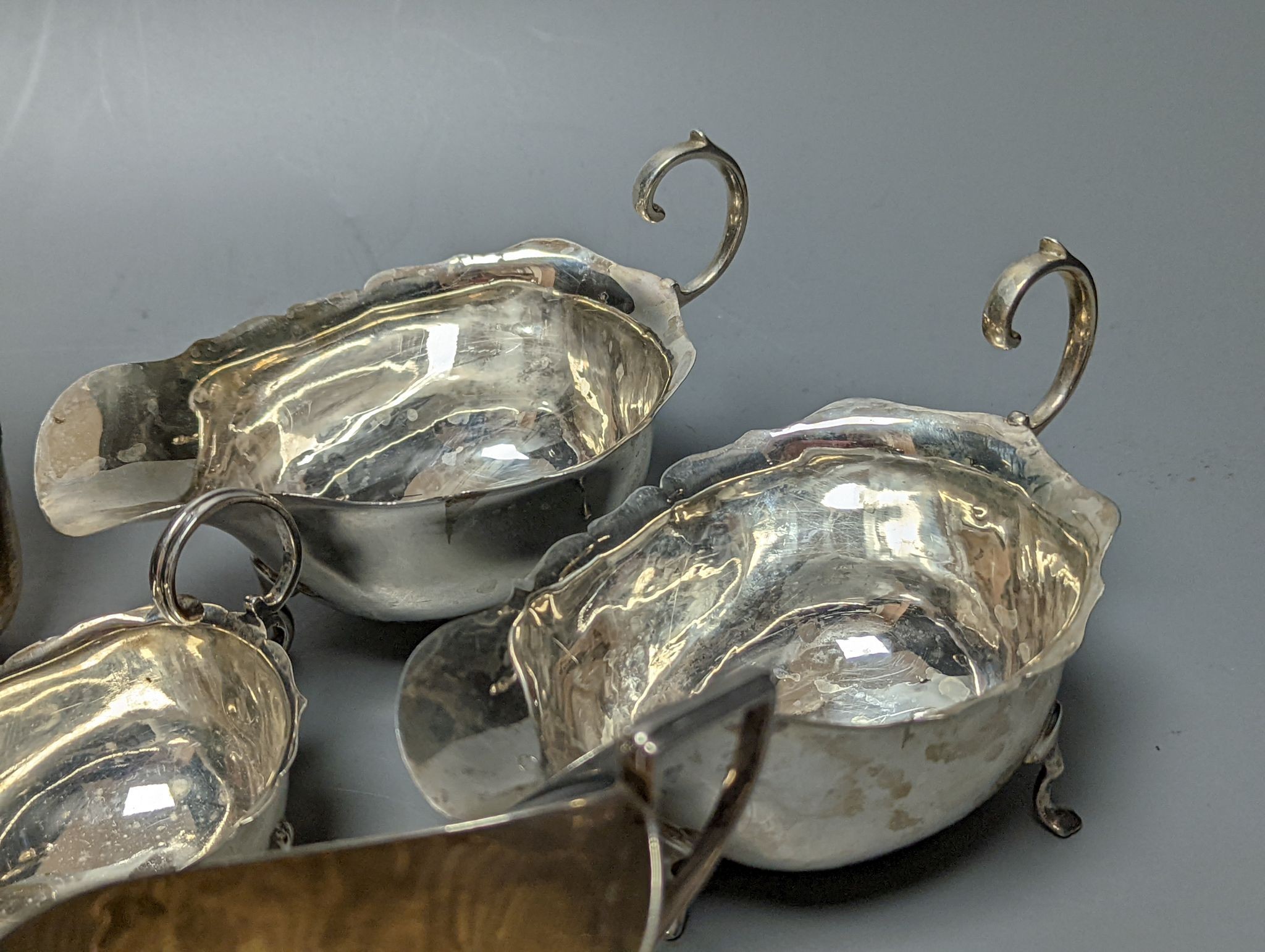 A group of assorted silver items including George V silver mounted hip flask(bruise), a pair of silver sauceboats(a.f.) one other sauceboat, sterling box, two silver cream jugs, cigarette box, salt, sugar tongs, brush an